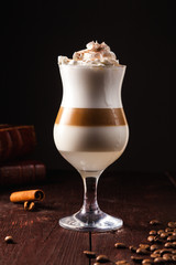 coffee cocktail based on espresso, white rum, coconut syrup and whipped cream in a transparent glass on a brown wooden table. Alcoholic coffee cocktail. Alcohol drink