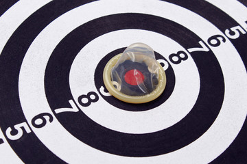 Unpacked condom on the background of a dartboard target (darts), toned