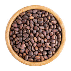 Pine nuts in wooden bowl isolated on white. Top view.