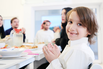 Fototapeta premium little muslim boy praying with family before iftar dinner