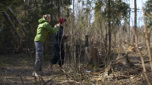 Two eco activists take pictures of illegally sawn tree in the forest and make notes on the paper. Conservationists protecting forest. Bright sunny spring day.