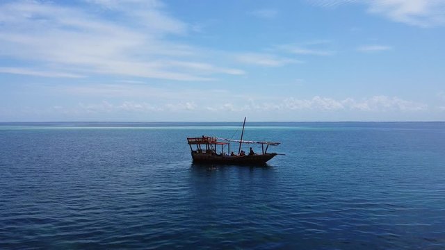 aerial shot of an old boat in the middle of the tropical sea of Tanzania by drone