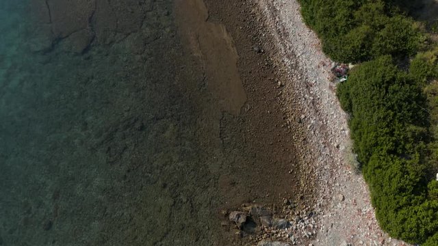 A person enjoying the water on the rocky shoreline by the road in Eubea Island, Greece - aerial