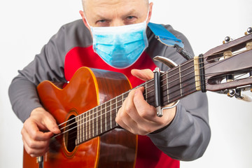 man in a medical mask plays the classical guitar on a white background. musical creativity. string...