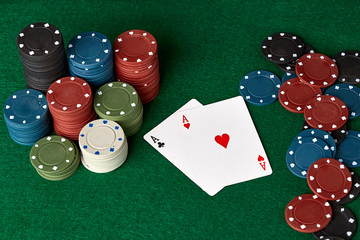 Poker chips and cards on a green poker canvas. Gambling, poker, casino concept. Black background. Close-up.