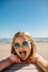 Playful girl at the beach sticking out her tongue
