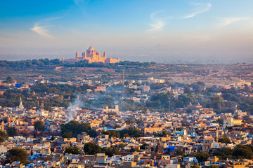 Aerial view of Jodhpur cityscape - the Blue city - with Umaid Bhawan Palace on horizon on sunset. View from Mehrangarh Fort. Jodphur, Rajasthan, India