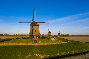 Naklejka premium Aerial view on three dutch windmills bathing in sunlight with a blue sky 