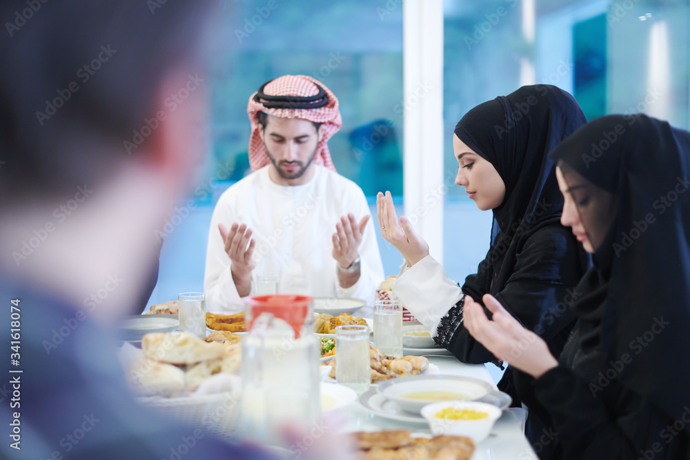 Wall mural traditional muslim family praying before iftar dinner