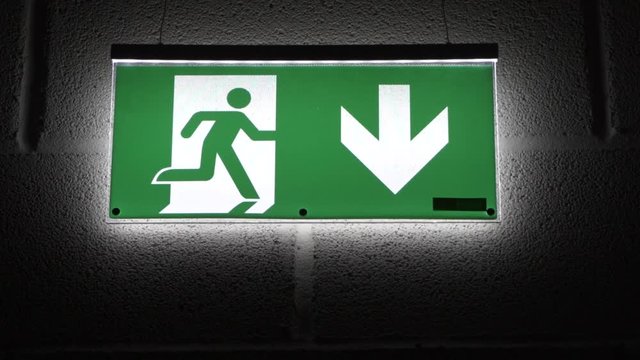 Green emergency exit sign hanging on the wall
