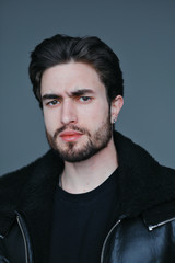 Obraz premium A large portrait of a stylish young man with a beard and dark hair in a black leather jacket