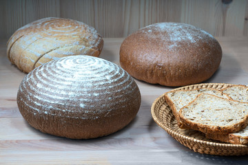 sliced ​​bread slices in a straw basket and round loaves of wheat bread on the kitchen table. Healthy eating concept