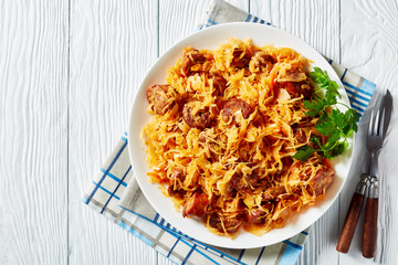 Cabbage stew with sausages on a white plate