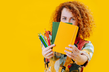 Female artist with gorgeous red curly hair looking over notebooks and crayons