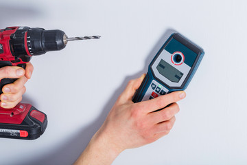 Man hand is scanning wall by cable detector to find a cable before drilling in.