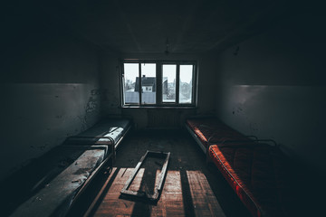 pokój ze zniszczonymi łózkami w opuszczonym budynku internatu