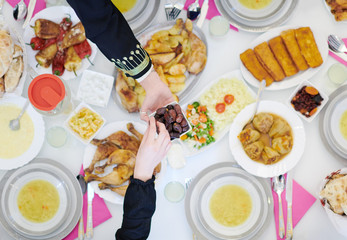 Muslim family having Iftar dinner eating dates to break feast top view