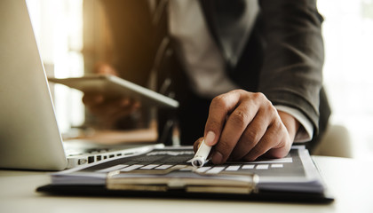 business documents on office table with smart phone and digital tablet and graph financial and man working
