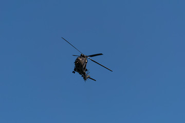 A military helicopter banks towards the camera on a warm spring afternoon during the Coronavirus...