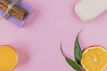 Home spa concept. On a blue background, items accompanying personal care: lavender and peach soap and mango cream for face and body after. For aromatherapy: cinnamon sticks, sliced orange