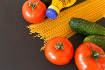 Various products. Spaghetti, pasta, tomatoes, cucumbers and vegetable sunflower oil on a gray background with place for text.