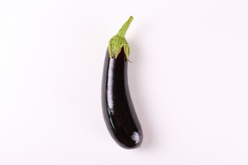 One single ripe organic polished eggplant laid on white background. Aubergine vegetable at table counter. Clean eating concept. Background, close up, flat lay, top view.