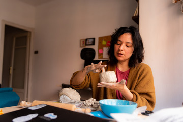 young artisan woman working at home with clay, a manual work that requires craftsmanship and skills, also a hobby and a pastime