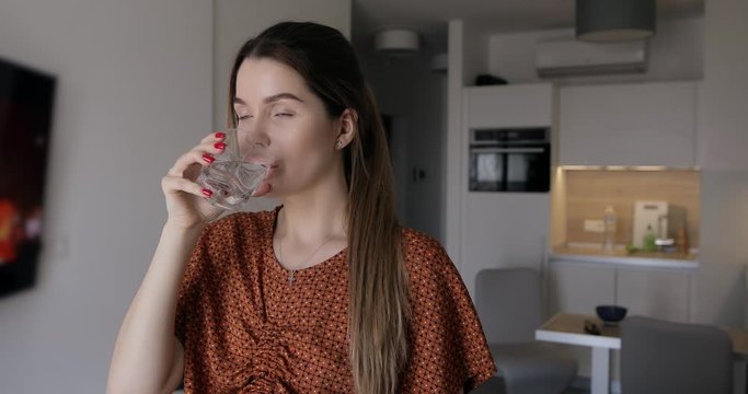 Woman drinking water at home for refreshing her health