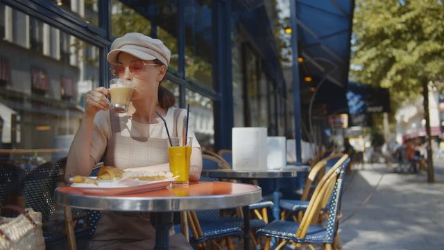 Happy girl having breakfast in the outdoor cafe in Paris