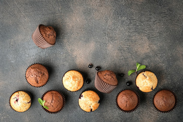 Chocolate and vanilla muffins on a portioned board on a dark background top view copy space.