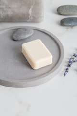 Hand soap at gray stone soap dish with lavender flower near at white marble in bathroom.