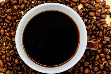 Coffee cup on wooden kitchen table. Top view with morning sunlight