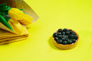 Flowers and cake. Monochrome stylish and trendy composition in yellow color on studio background. Top view, flat lay. Pure beauty of usual things around. Copyspace for ad. Holiday, food, fashion.