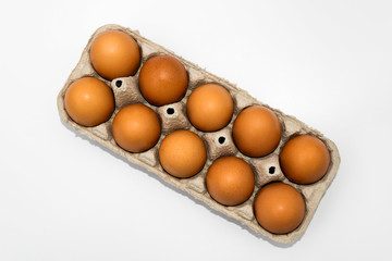 Chicken eggs in cardboard egg box on white background. Raw chicken eggs in open egg box on a white background. Eggs in the package. Top Veiw
