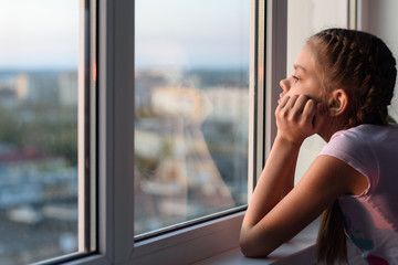 The girl in self-isolation looks out the window