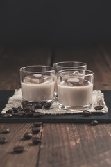 Glasses of Cream coffee liqueur with ice, and coffee  beans on rustic wooden background.