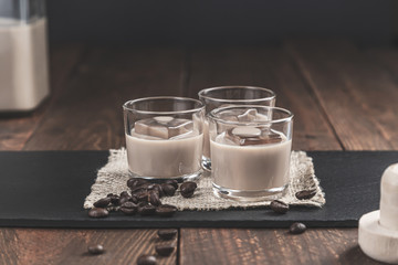 Glasses of Cream coffee liqueur with ice, and coffee  beans on rustic wooden background.