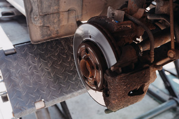 change the old drive to the Brand new brake disc on car in a garage. Auto mechanic repairing .