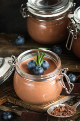Chocolate mousse in glass jar with berries on a rustic background copy space. Homemade dessert.
