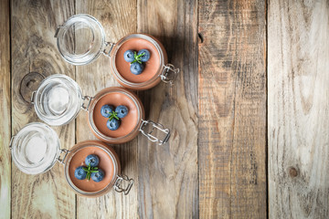 Chocolate mousse in glass jar with berries on a rustic background copy space. Homemade dessert.