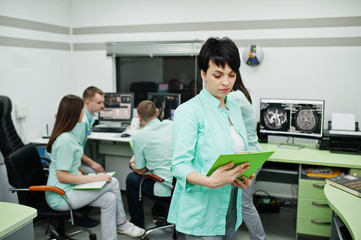 Medical theme .Portrait of female doctor with clipboard against group of doctors meeting in the mri office at diagnostic center in hospital.