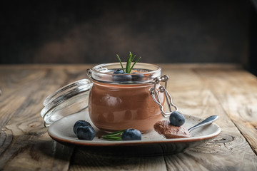 Chocolate mousse in glass jar with berries on a rustic background copy space. Homemade dessert.