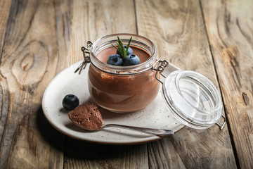 Chocolate mousse in glass jar with berries on a rustic background copy space. Homemade dessert.