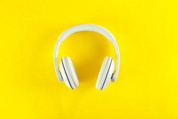 Minimalistic top view composition with white headphones on bright paper textured background with a...
