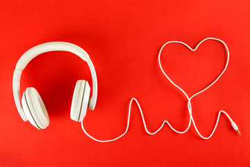 Minimalistic top view composition with white headphones on bright paper textured background with a...