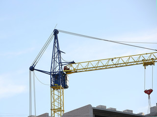 Tower cranes work during the construction of a multi-story building. New apartments for residents and premises for offices. Risky work at height. Lifting heavy building materials. City development