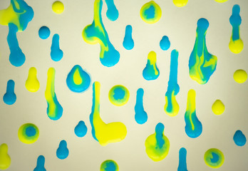 Yellow and blue drops of paint on white paper.