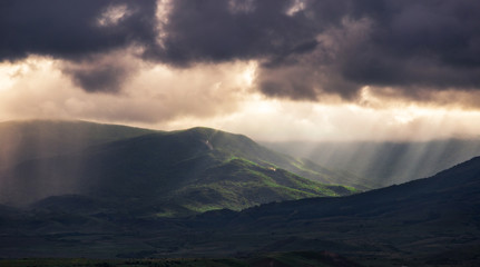  Landscape of forest on the hills and gray sky after rain with rays from the sun.