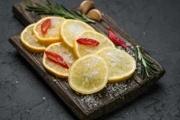 Selection of spices, herbs and lemon. Ingredients for cooking. Food background on black slate table. Top view copy space.
