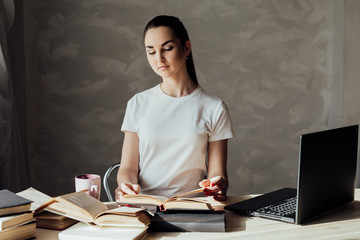 beautiful young woman sitting at a table with books for education and exams